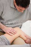 Physiotherapist looking at the knee of his patient