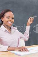 Smiling teacher showing the blackboard with her glasses