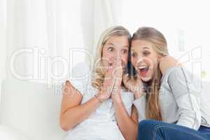 A shocked and happy pair of girls making a phone call