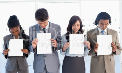 Young business team showing blank sheets while bowing their head