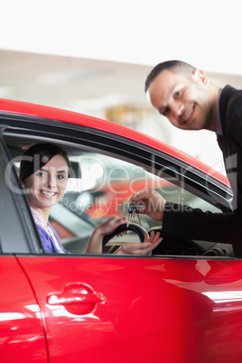 Happy salesman giving car keys to a woman