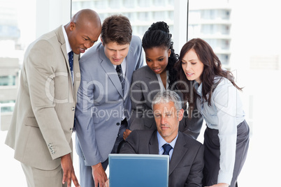Mature manager giving explanations to his team with a laptop