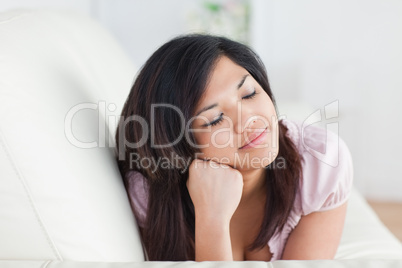 Woman closing her eyes while resting on a couch