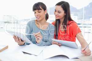 Two smiling students using tablets with one girl looking at the