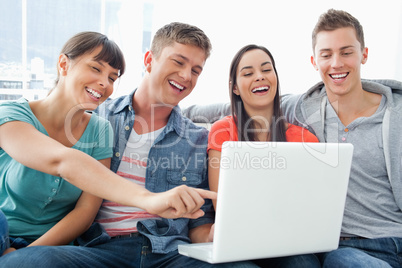 A group of smiling friends gathered around a laptop