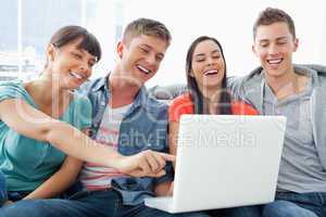 A group of smiling friends gathered around a laptop