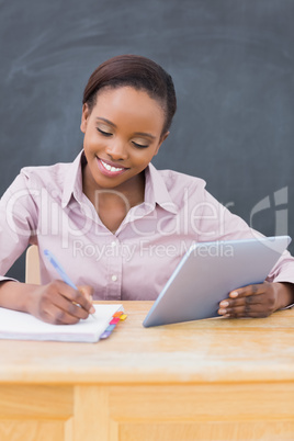 Teacher holding an ebook while writing