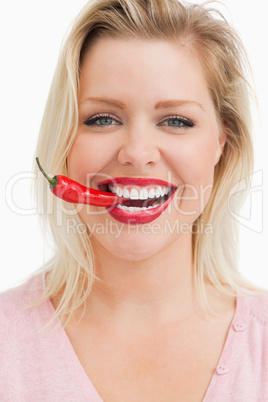 Happy blonde woman biting a chili