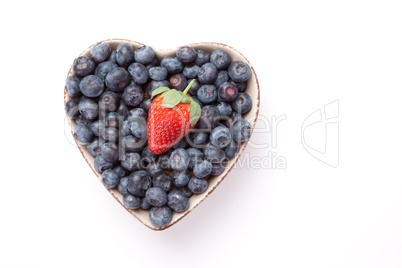 Blueberries and one Strawberry  in  a heart shaped bowl