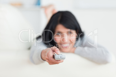 Woman lying on a sofa while holding a television remote