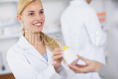 Blonde pharmacist giving a drug box