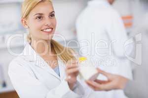 Blonde pharmacist giving a drug box