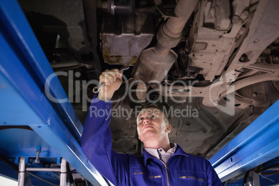 Concentrated mechanic repairing below of a car