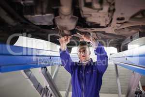 Concentrated mechanic repairing a car with tools