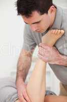 Physiotherapist manipulating the leg of a woman while she is lyi
