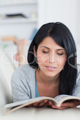 Woman reading a book while relaxing on a sofa