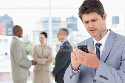 Young manager sending a text with his mobile phone in a concentr
