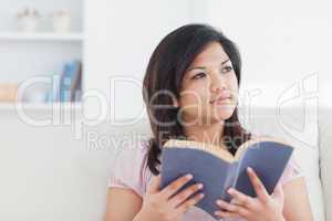 Woman sitting on a sofa while holding a book