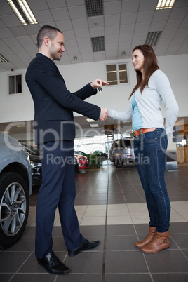 Salesman giving car keys while shaking hand of a client