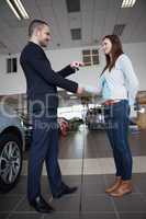 Salesman giving car keys while shaking hand of a client