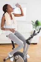 Black woman doing exercise bike while drinking