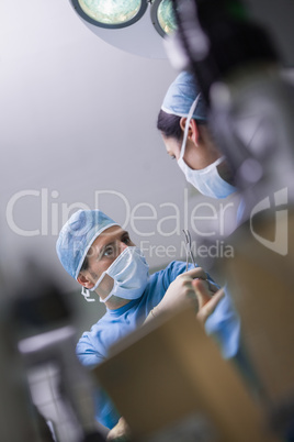 Serious doctor giving a surgical scissor to a nurse