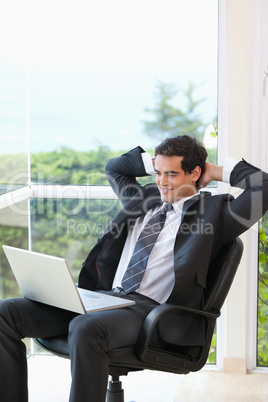 Men sitting in a chair looking at a laptop
