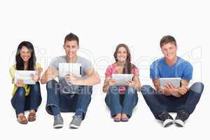A group of people sitting beside each other with tablets while l