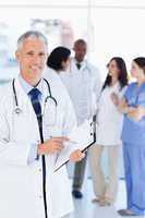 Smiling doctor pointing at a word on his clipboard