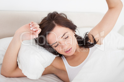 Peaceful woman stretching her body while lying