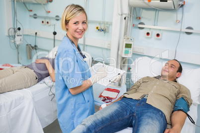 Nurse looking at camera next to transfused patients