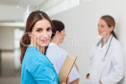 Nurse in a hallway with a doctor and a patient while holding fil