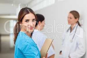 Nurse in a hallway with a doctor and a patient while holding fil