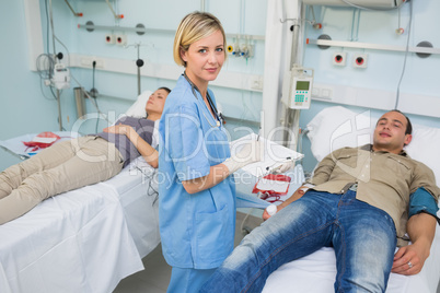 Two patients lying on bed next to a nurse