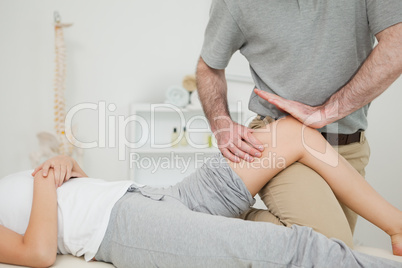 Serious osteopath massaging the knee of a patient