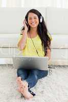 Portrait of a smiling Latin listening to music on a laptop