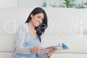 Smiling woman holding a magazine while sitting on the floor