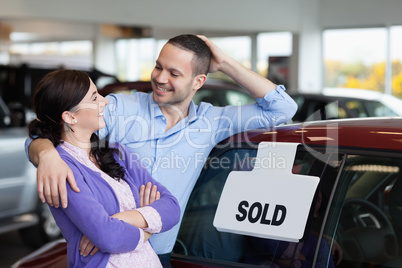 Smiling couple hugging next to a car