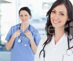 Smiling nurse standing upright while leaning her head to the sid