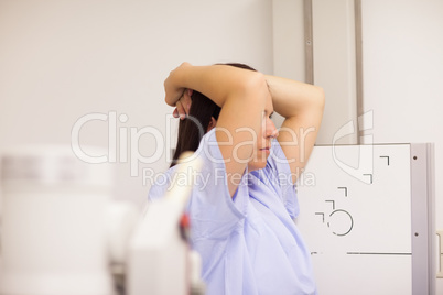 Patient placing her arms on her head while standing in front of