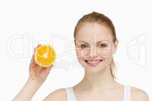 Cheerful woman presenting an orange
