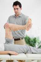 Brunette physiotherapist manipulating a leg