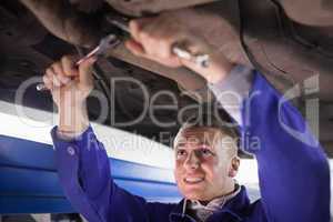 Mechanic repairing a car while using tools