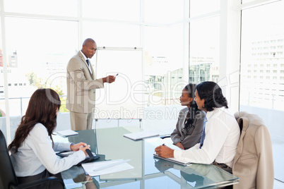 Businessman pointing to something on the flipchart to explain th