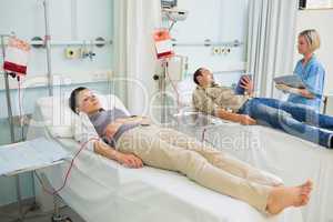 Two transfused patients lying on a medical bed