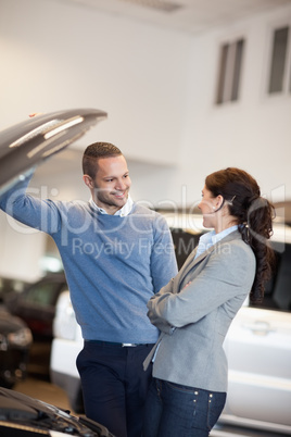 Smiling couple in front of an open car engine