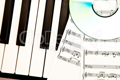 Compact disc and music scores placed on piano