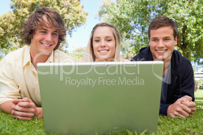 Three smiling students in a park