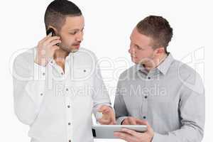 Two people discussing while phoning and holding a tablet compute