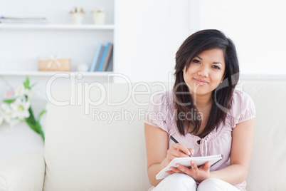 Woman smiling while writing on a notebook